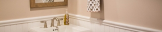 detail of pedestal sink and wainscoting on wall in remodeled bathroom