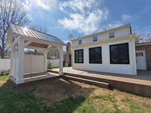 Kremser - new addition with white siding and black frame windows on a new deck with pergola