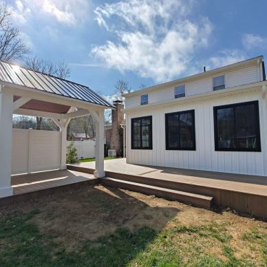 Kremser - new addition with white siding and black frame windows on a new deck with pergola